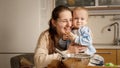 Portrait of happy smiling mother hugging her little baby son covered in dough and flour while baking cake or bread at Royalty Free Stock Photo