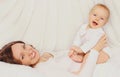Portrait of happy smiling mother and little baby lying and playing on bed at home Royalty Free Stock Photo
