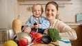 Portrait of happy smiling mother with little baby son having fun on kitchen while cooking. Concept of little chef Royalty Free Stock Photo