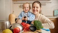 Portrait of happy smiling mother with little baby son having fun on kitchen while cooking. Concept of little chef, children Royalty Free Stock Photo