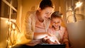 Portrait of happy smiling mother with little son playing and having fun with tablet computer in tent or small house at Royalty Free Stock Photo