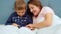 Portrait of happy smiling mother with little toddler son playing on tablet computer while lying in bed Royalty Free Stock Photo