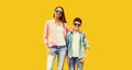 Portrait of happy smiling mother with son teenager in sunglasses, checkered shirts on yellow background Royalty Free Stock Photo