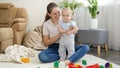 Portrait of happy smiling mother supporting her little baby son standing on acrpet in living room Royalty Free Stock Photo