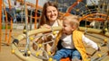 Portrait of happy smiling mother swinging her baby son on the playground on sunny day. Children playing outdoor, kids outside, Royalty Free Stock Photo