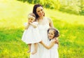 Portrait of happy smiling mother with two daughters children on the grass in summer park Royalty Free Stock Photo