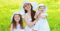 Portrait happy smiling mother with two daughters children wearing a summer straw hats on the grass in a park Royalty Free Stock Photo