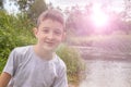 Portrait of happy smiling preteen boy outdoors in summertime, green nature and sunlight on background Royalty Free Stock Photo