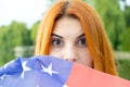 Portrait of happy smiling red haired girl hiding her face behind USA national flag Royalty Free Stock Photo