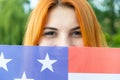 Portrait of happy smiling red haired girl hiding her face behind USA national flag. International day of democracy concept Royalty Free Stock Photo