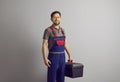 Portrait of a happy smiling repairman holding a tool box isolated on gray background. Royalty Free Stock Photo