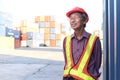 Portrait of happy smiling senior elderly Asian worker engineer wearing safety vest and helmet, standing at logistic shipping cargo