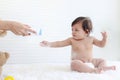 Portrait of happy smiling toddle baby girl sit on fluffy white rug with mother hand hold dusting powder bottle, mom apply talcum Royalty Free Stock Photo