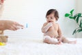 Portrait of happy smiling toddle baby girl sit on fluffy white rug with mother hand hold dusting powder bottle, mom apply talcum Royalty Free Stock Photo