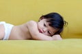 Portrait of happy smiling toddle baby kid lying on yellow sofa in living room at home, little girl daughter spending time at home Royalty Free Stock Photo