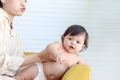 Portrait of happy smiling toddle baby lying on yellow sofa in living room at home, mother bonding with little girl daughter, mom Royalty Free Stock Photo