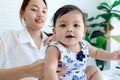 Portrait of happy smiling toddle baby sitting in living room with her mother, little cute kid girl plays with her parent, mom Royalty Free Stock Photo