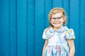 Portrait of happy smiling toddler girl in blue clothes outdoors. Little child with blond hairs looking and smiling at Royalty Free Stock Photo