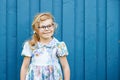 Portrait of happy smiling toddler girl in blue clothes outdoors. Little child with blond hairs looking and smiling at Royalty Free Stock Photo