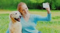 happy smiling woman with Golden Retriever dog taking selfie a picture by phone in a park Royalty Free Stock Photo