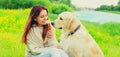 Portrait of happy smiling woman with her Golden Retriever dog on green grass in summer park Royalty Free Stock Photo