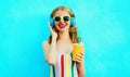 Portrait happy smiling woman holding cup of juice listening to music in wireless headphones on colorful blue Royalty Free Stock Photo