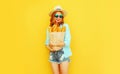 portrait happy smiling woman holding paper bag with long white bread baguette, wearing straw hat, shorts on colorful yellow Royalty Free Stock Photo
