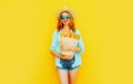 portrait happy smiling woman holding paper bag with long white bread baguette, wearing straw hat, shorts on colorful yellow Royalty Free Stock Photo