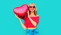 Portrait happy smiling woman holding red heart shaped air balloon on colorful blue Royalty Free Stock Photo