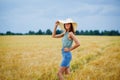 Portrait of a happy smiling woman with long hair, skirt and hat standing in a wheat field Royalty Free Stock Photo