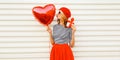 Portrait of happy smiling woman with red heart shaped balloon and gift box wearing beret and skirt on white background Royalty Free Stock Photo