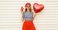 Portrait of happy smiling woman with red heart shaped balloon and gift box wearing beret and skirt on white background Royalty Free Stock Photo