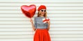 Portrait of happy smiling woman with red heart shaped balloon and gift box wearing beret and skirt on white background Royalty Free Stock Photo