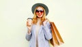 Portrait happy smiling woman with shopping bags, holding coffee cup, wearing pink coat, round hat on background Royalty Free Stock Photo
