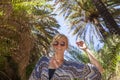 Portrait of happy smiling woman with sunglasses by branches of palm trees at tropical coast in Preveli beach on Crete island Royalty Free Stock Photo