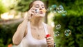 Portrait of happy smiling young woman blowing colorful soap bubbles at summer park Royalty Free Stock Photo