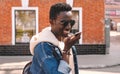 Portrait happy smiling young african man with smartphone using voice command recorder, assistant or takes calling on city street Royalty Free Stock Photo