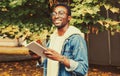 Portrait of happy smiling young african man student reading a book wearing eyeglasses in autumn city park Royalty Free Stock Photo