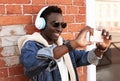 Portrait happy smiling young african man taking selfie by smartphone listening to music in headphones on a city street Royalty Free Stock Photo