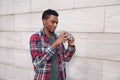 Portrait happy smiling young african man with vintage film camera taking picture walking on city street over gray brick wall Royalty Free Stock Photo