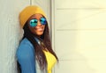 Portrait of happy smiling young african woman model wearing sunglasses, yellow hat, colorful clothes in the city Royalty Free Stock Photo