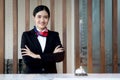 Portrait of happy smiling young beautiful Asian female receptionist in black suit confidential standing with arms crossed at hotel Royalty Free Stock Photo