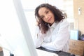 Portrait of happy smiling young beautiful woman with curly hair using desktop computer, female officer staff in casual white shirt Royalty Free Stock Photo