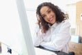 Portrait of happy smiling young beautiful woman with curly hair using desktop computer, female officer staff in casual white shirt Royalty Free Stock Photo