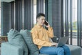 Portrait of happy smiling young business Asian, Chinese man person using laptop computer, working, and talking on smart mobile Royalty Free Stock Photo
