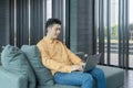 Portrait of happy smiling young business Asian, Chinese man person using laptop notebook computer, working online on couch sofa in Royalty Free Stock Photo