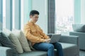 Portrait of happy smiling young business Asian, Chinese man person using laptop notebook computer, working online on couch sofa in Royalty Free Stock Photo