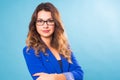 Portrait of happy smiling young cheerful businesswoman in glasses over blue background. Caucasian brunette model in Royalty Free Stock Photo