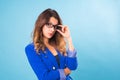Portrait of happy smiling young cheerful businesswoman in glasses over blue background. Caucasian brunette model in Royalty Free Stock Photo