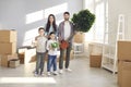 Portrait of happy young family with kids standing in their new home on moving day Royalty Free Stock Photo